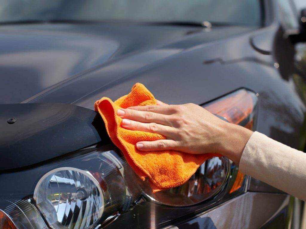 Hand with a cloth cleaning a car